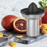 Blood oranges, citrus press and a glass of juice.